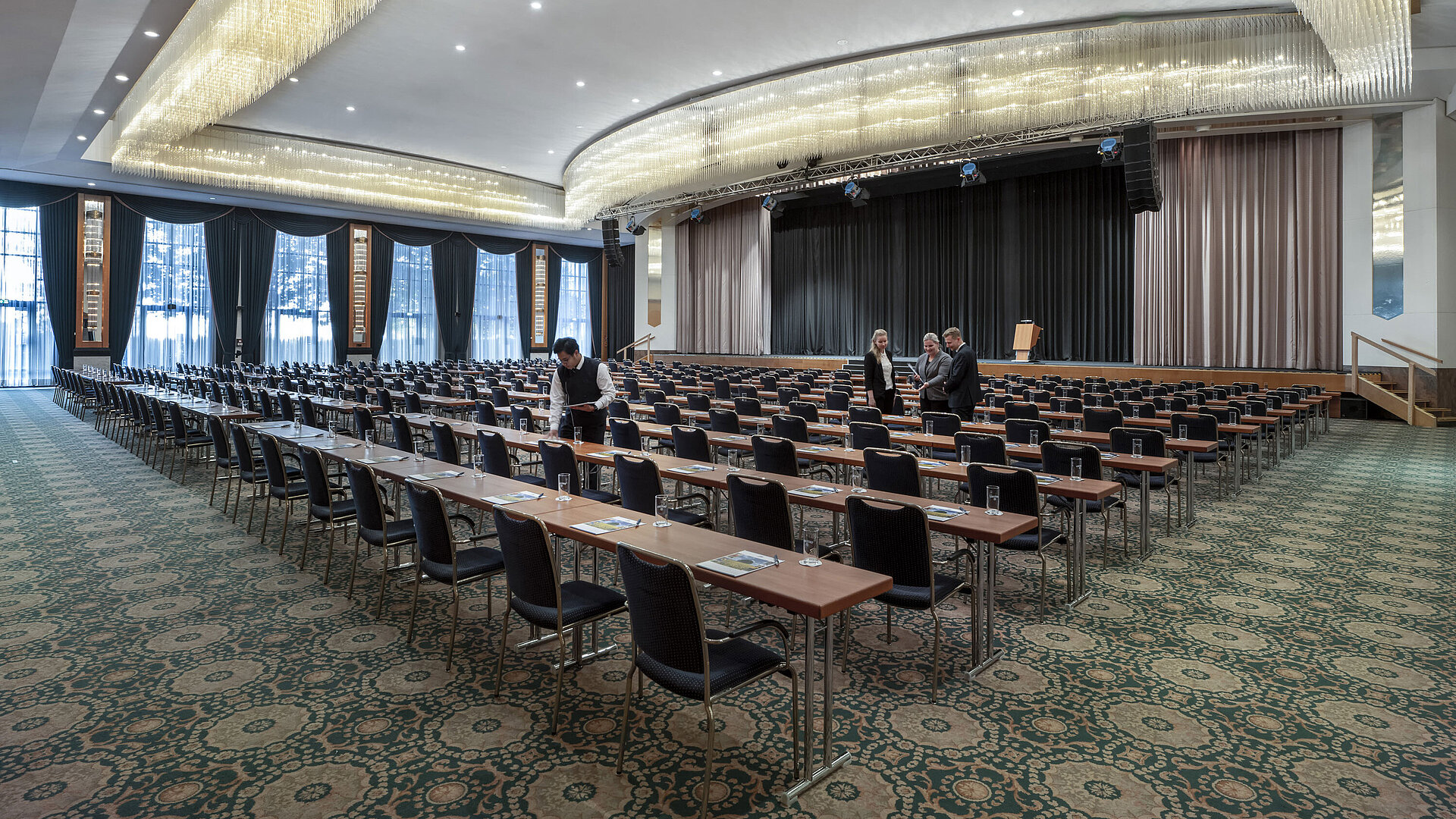 Saal Maritim Magnificent hall at the Maritim Hotel Magdeburg with a stage, row seating, and luxurious chandelier.