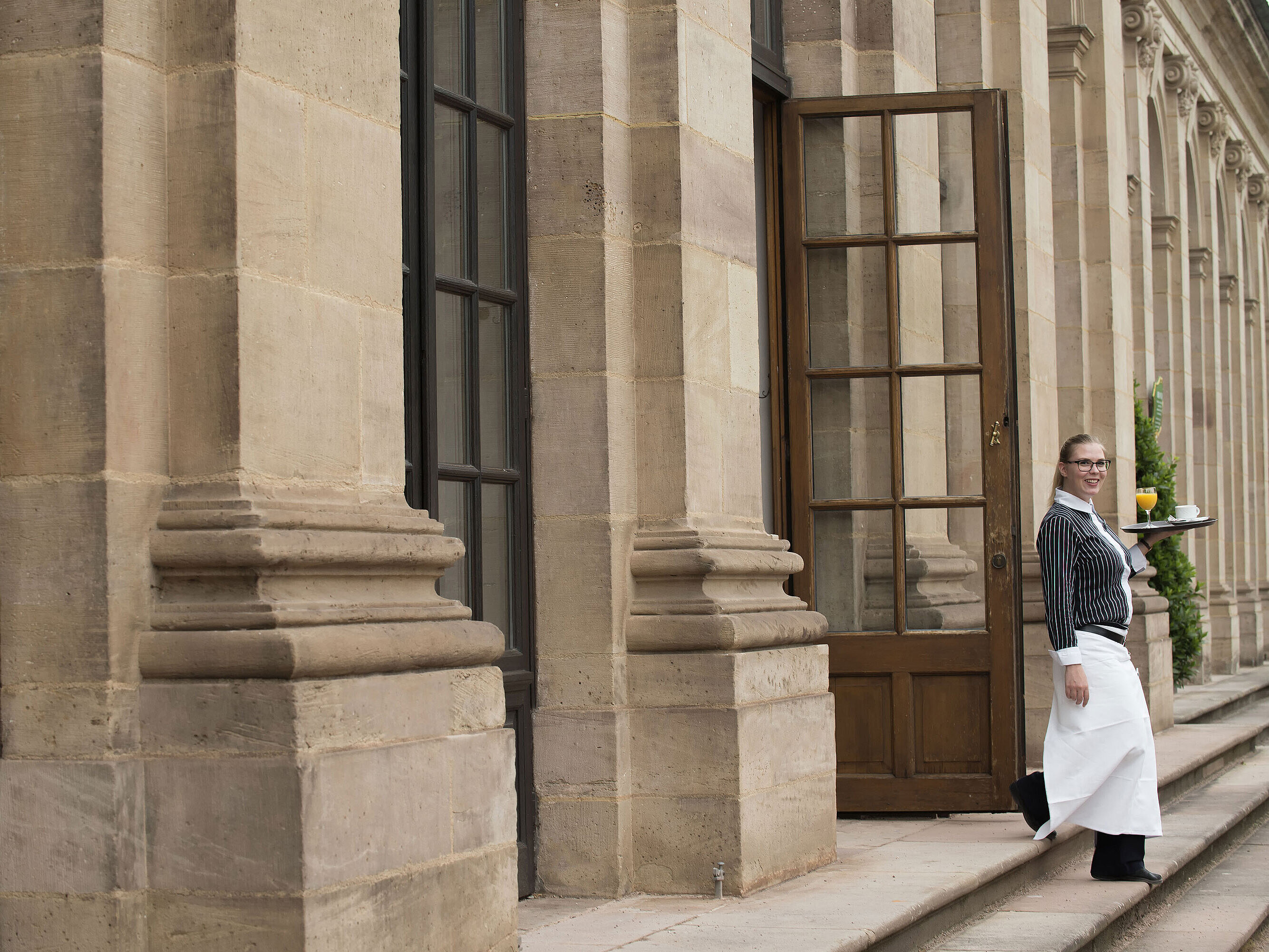 Maritim Service Friendly waitress serving breakfast with freshly squeezed orange juice on the terrace of Maritim Hotel Fulda.