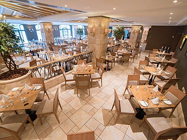 Les Jardins - Main Restaurant Elegant restaurant area with set tables, columns and bright interior design