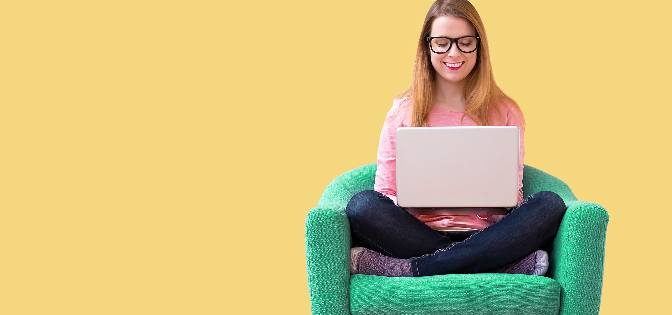 © AdobeStock 257087872 Woman sitting on a green armchair with a laptop on a yellow background working in a relaxed way