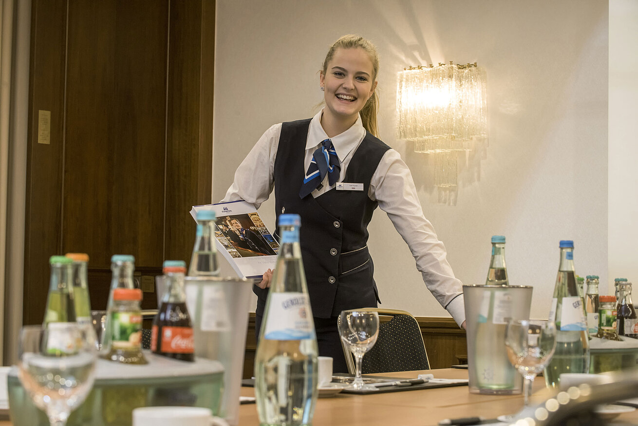 Salon Lenné Friendly service employee in the Salon Lenné of the Maritim Hotel Bonn with drinks and conference documents on the table.