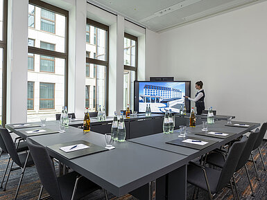 Meeting room Compact meeting room at Maritim Hotel Ingolstadt with large screen, modern technology, and natural light.