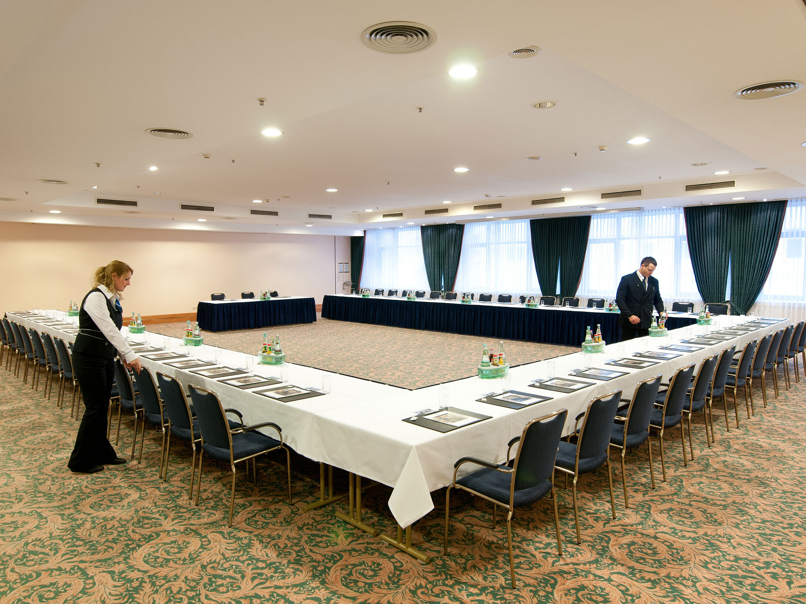 Saal Berlin Conference room at Maritim Hotel Magdeburg with U-shaped seating, set tables, and staff preparations.