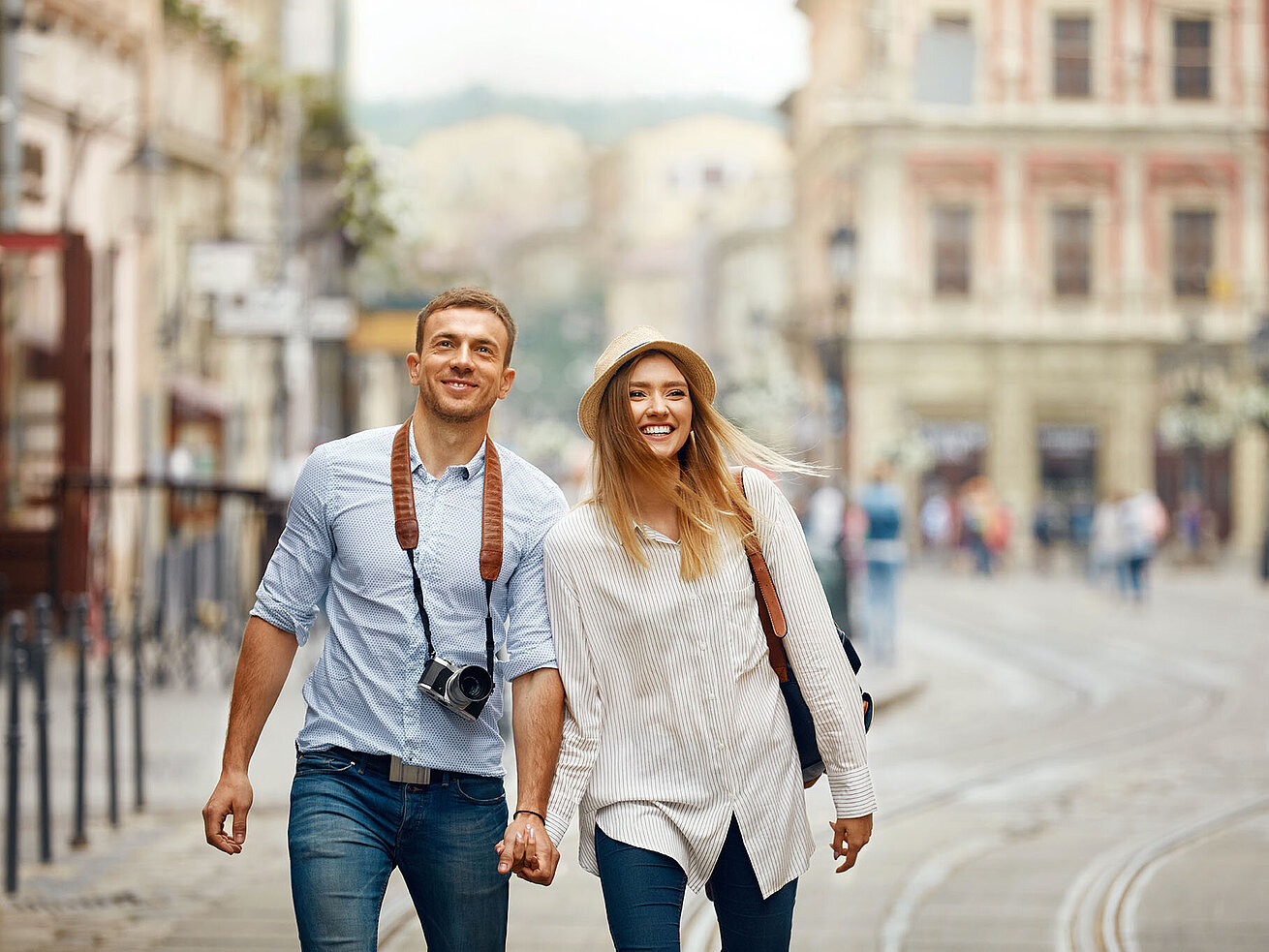 © puhhha - AdobeStock.com Happy couple walking hand in hand through a historic old town
