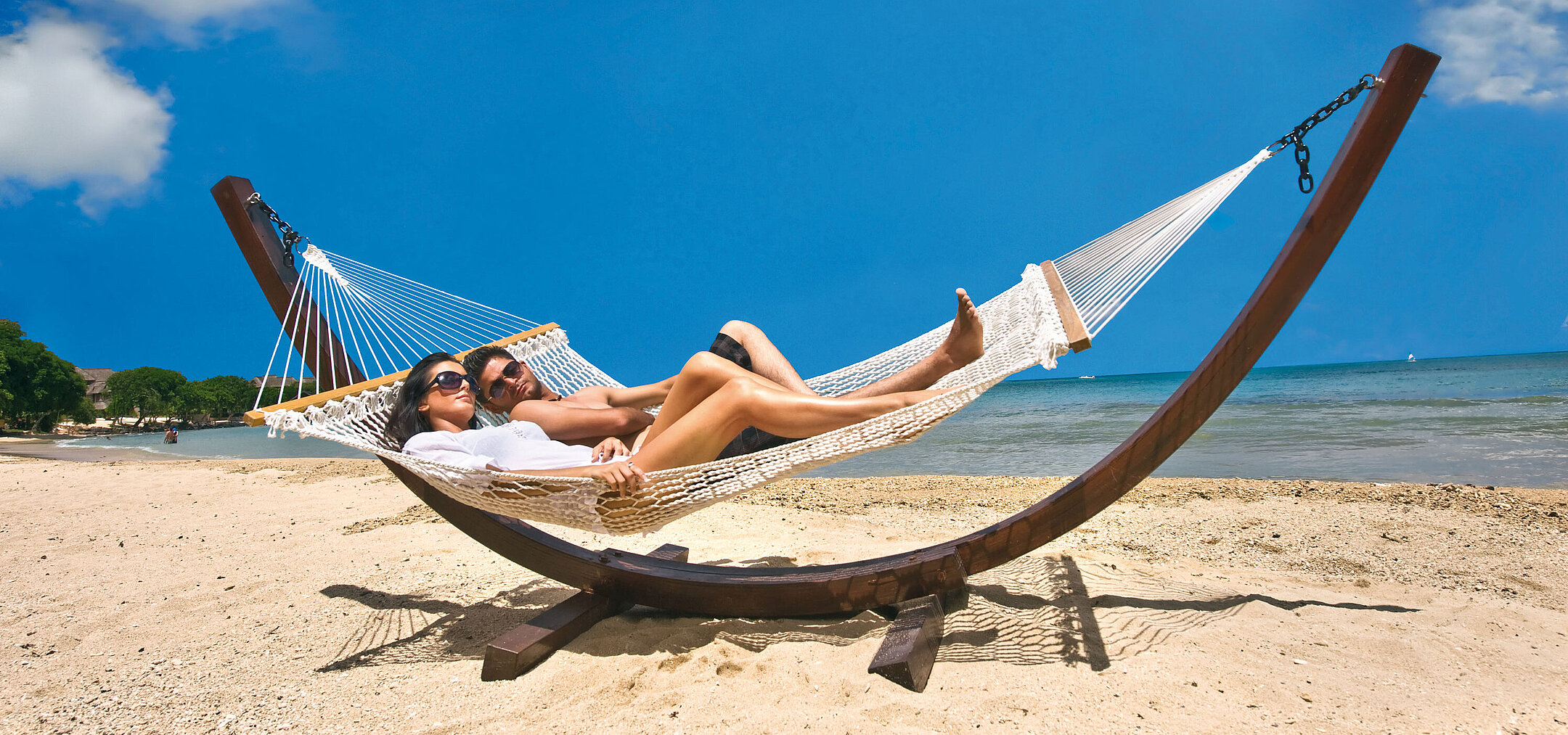 Hammock on the beach Couple relaxing in a hammock on a sandy beach with view of the blue sea