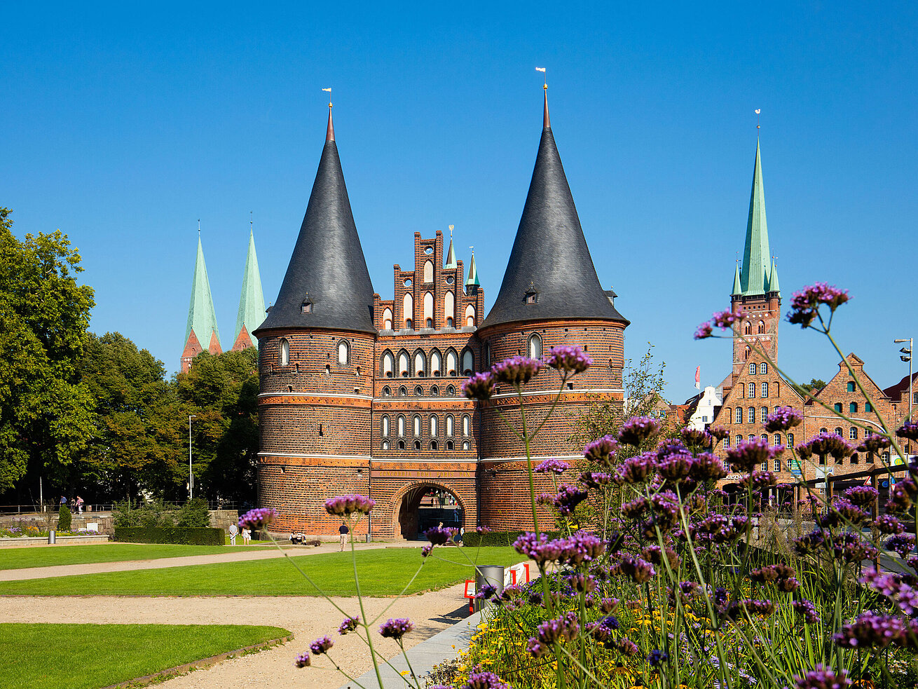 Holstentor Luebeck Holstentor in Lübeck with blooming flowers in the foreground and blue sky.