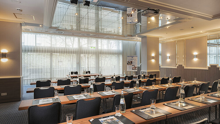 Saal München Meeting room with large windows, tables and water bottles at the Maritim Hotel Munich