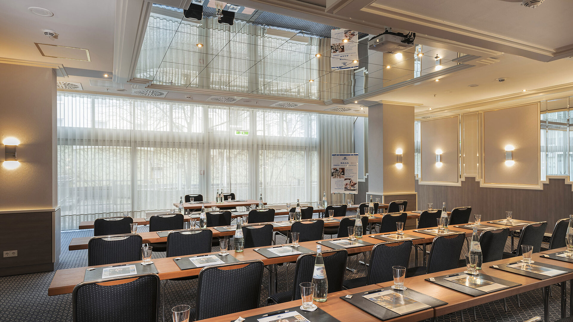 Saal München Meeting room with large windows, tables and water bottles at the Maritim Hotel Munich