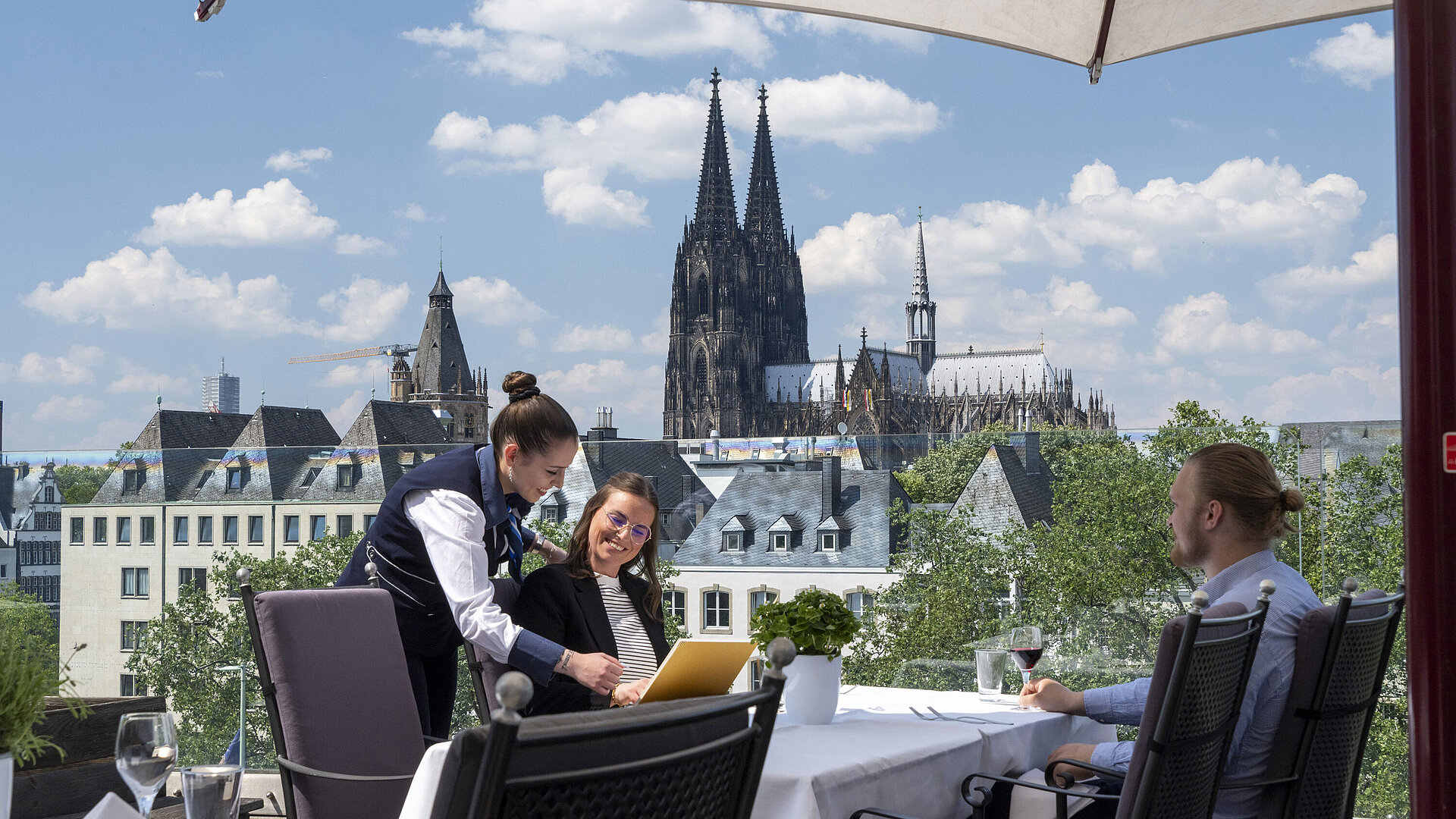 Rooftop terrace Guests enjoying service on the rooftop terrace of Maritim Hotel Cologne with views of Cologne Cathedral and the Old Town.