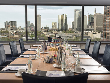 Skylounge Conference room at Maritim Hotel Frankfurt with a skyline view. Elegant table set with beverages and snacks for meetings.