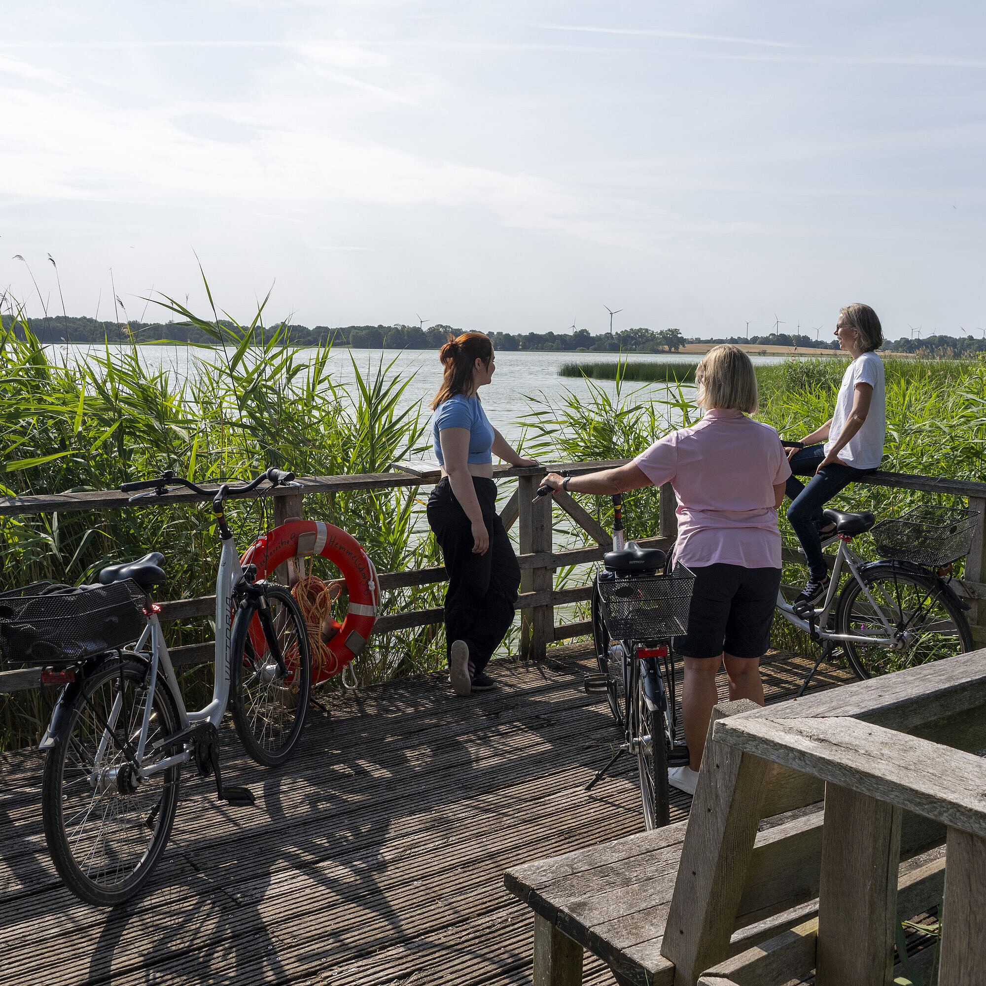 Bicycle tour Three women take a break during a bike tour on a pier overlooking the lake at Maritim Seehotel Timmendorfer Strand.