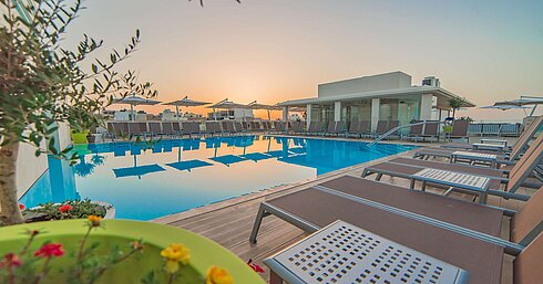 Pool Outdoor pool with sun loungers and parasols during atmospheric sunset