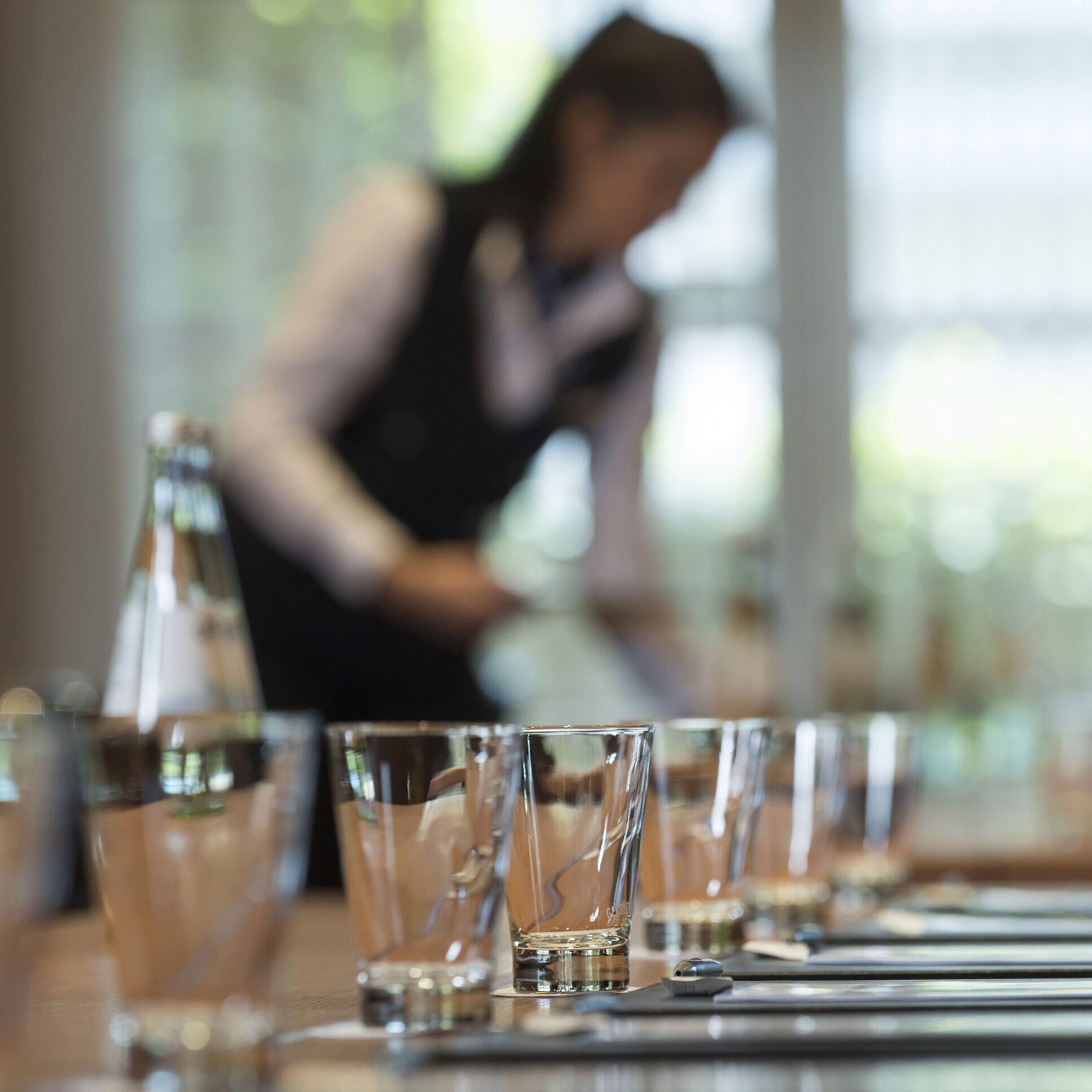 Preparing a meeting Staff member preparing conference table with glasses and water bottles for meeting