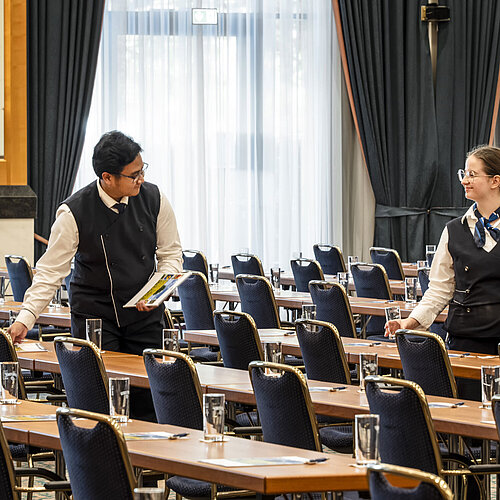 Maritim Conference Service Staff members at the Maritim Hotel Magdeburg preparing the hall with glasses and materials on the tables.