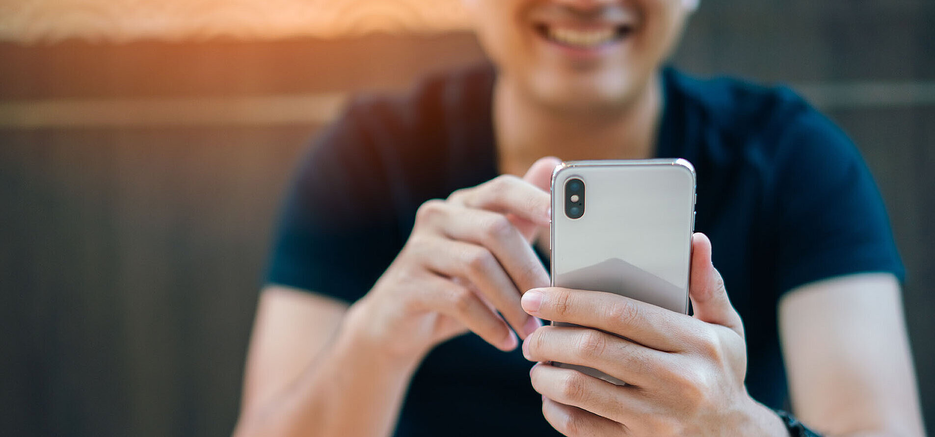 © Travel man - AdobeStock.com Man holding smartphone and smiling while typing a message