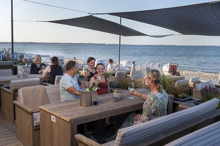Beach Lounge Group of guests at the beach bar of Maritim Seehotel Timmendorfer Strand enjoying drinks with sea view and beach chairs.