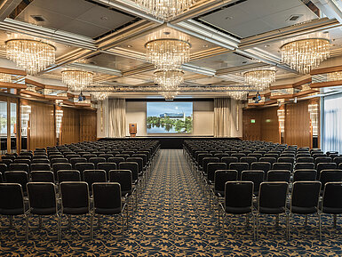 Saal Hannover Elegant event hall with crystal chandeliers, row seating, and a large stage at Maritim Hotel Hannover.