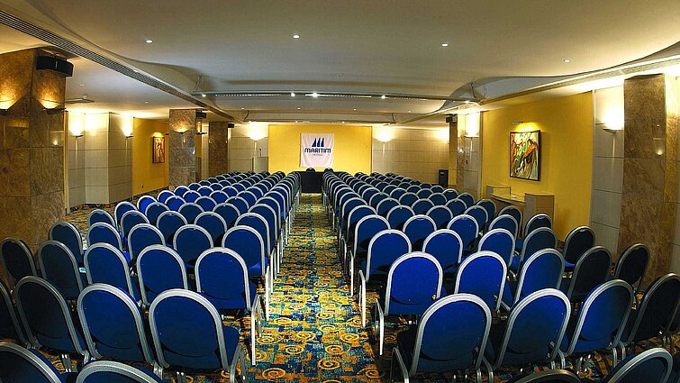 Melea Suite Bright conference room with theatre seating, stage and Maritim Hotels logo for meetings and events