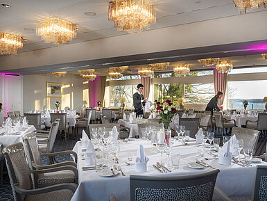 Salon Kopenhagen and Helsinki Salons Copenhagen and Helsinki in the Maritim Hotel Kiel, tables laid, chandeliers and sea view, staff arranging the room.