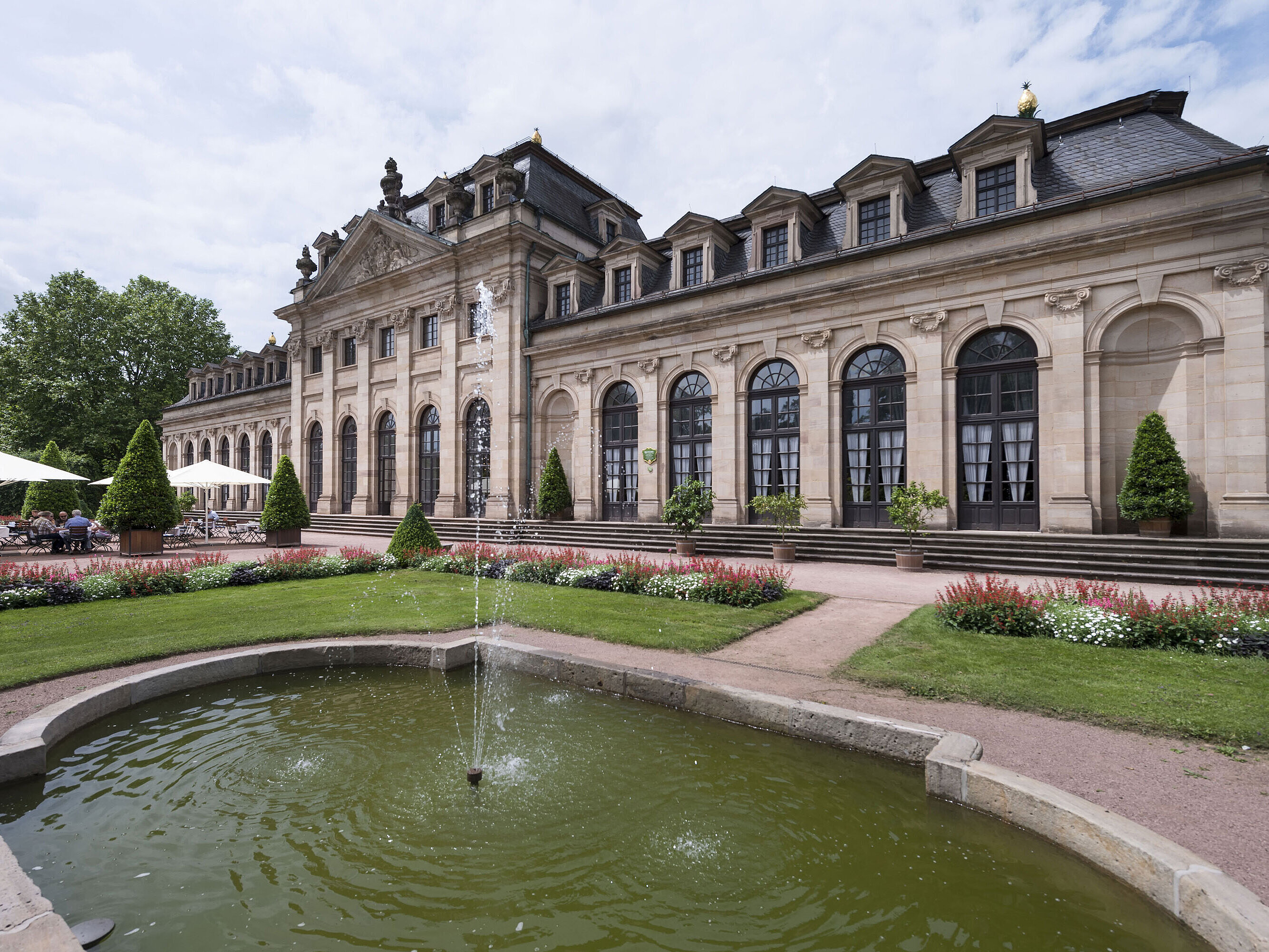 Exterior view The baroque Orangerie Fulda with terrace, manicured garden, and historic fountain in the foreground.
