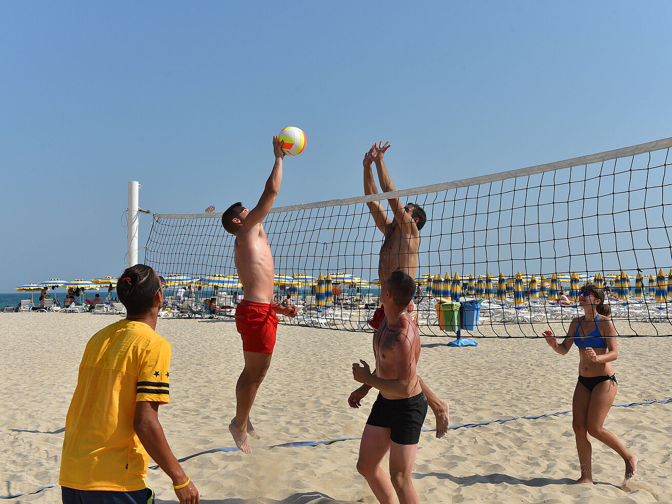 Beach Volleyball Beach volleyball match on the resort’s sandy beach with players at the net in sunny weather