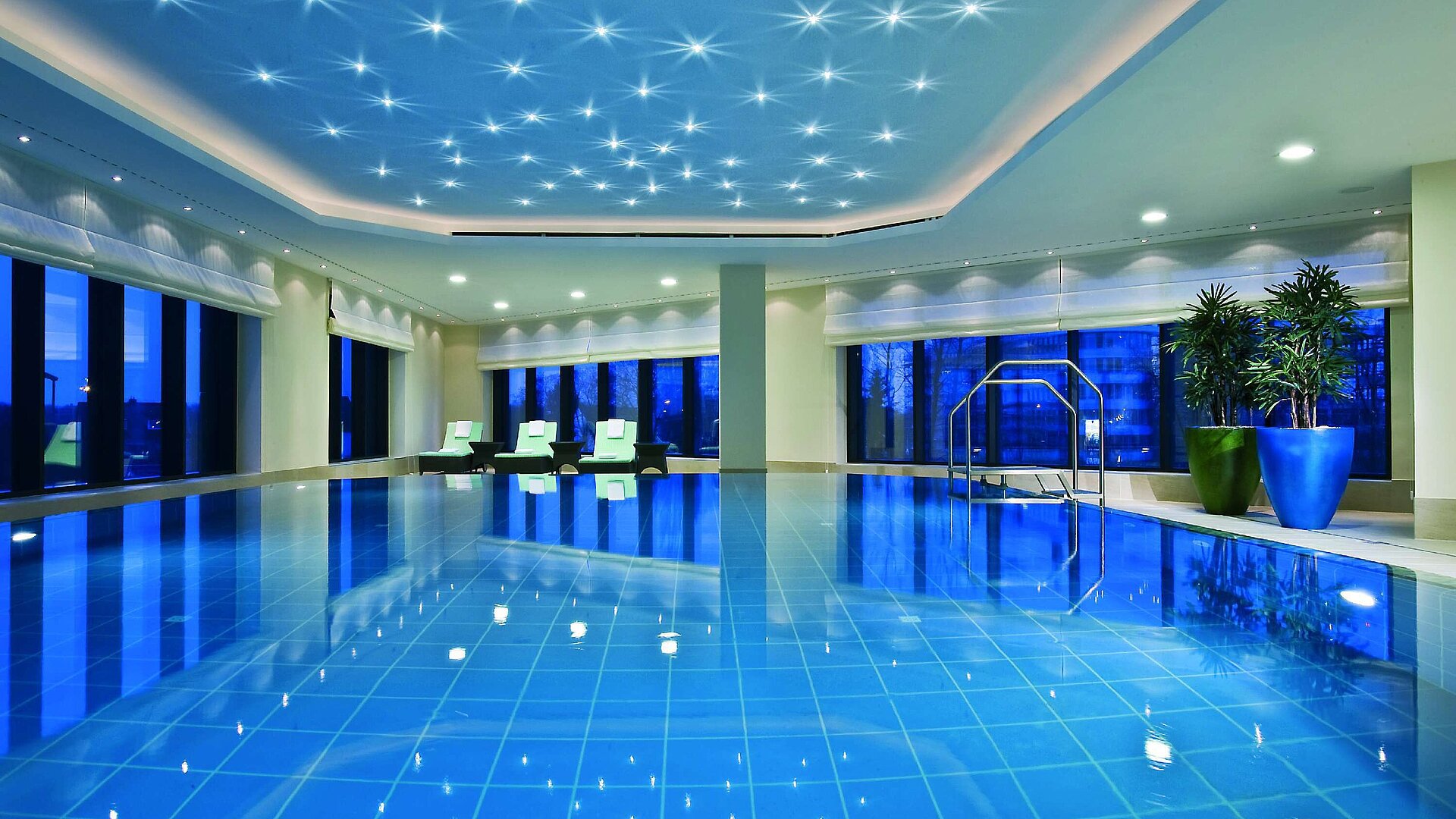 Pool Illuminated indoor pool at Maritim Hotel Düsseldorf with modern loungers and panoramic windows, perfect for relaxation.