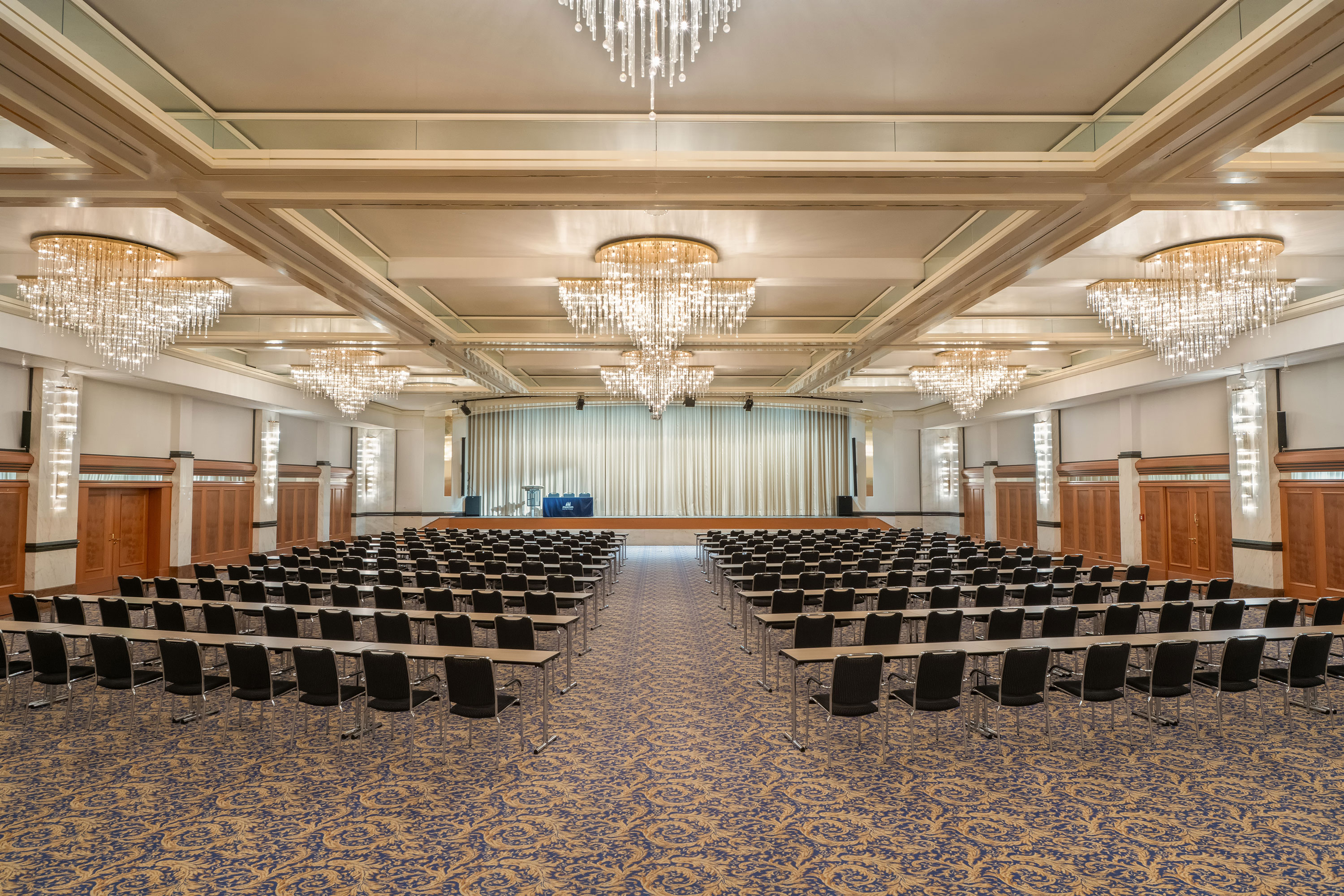 Fürst-von-Metternich-Saal Fürst-von-Metternich Hall with large stage, row seating, elegant chandeliers and bright interior.