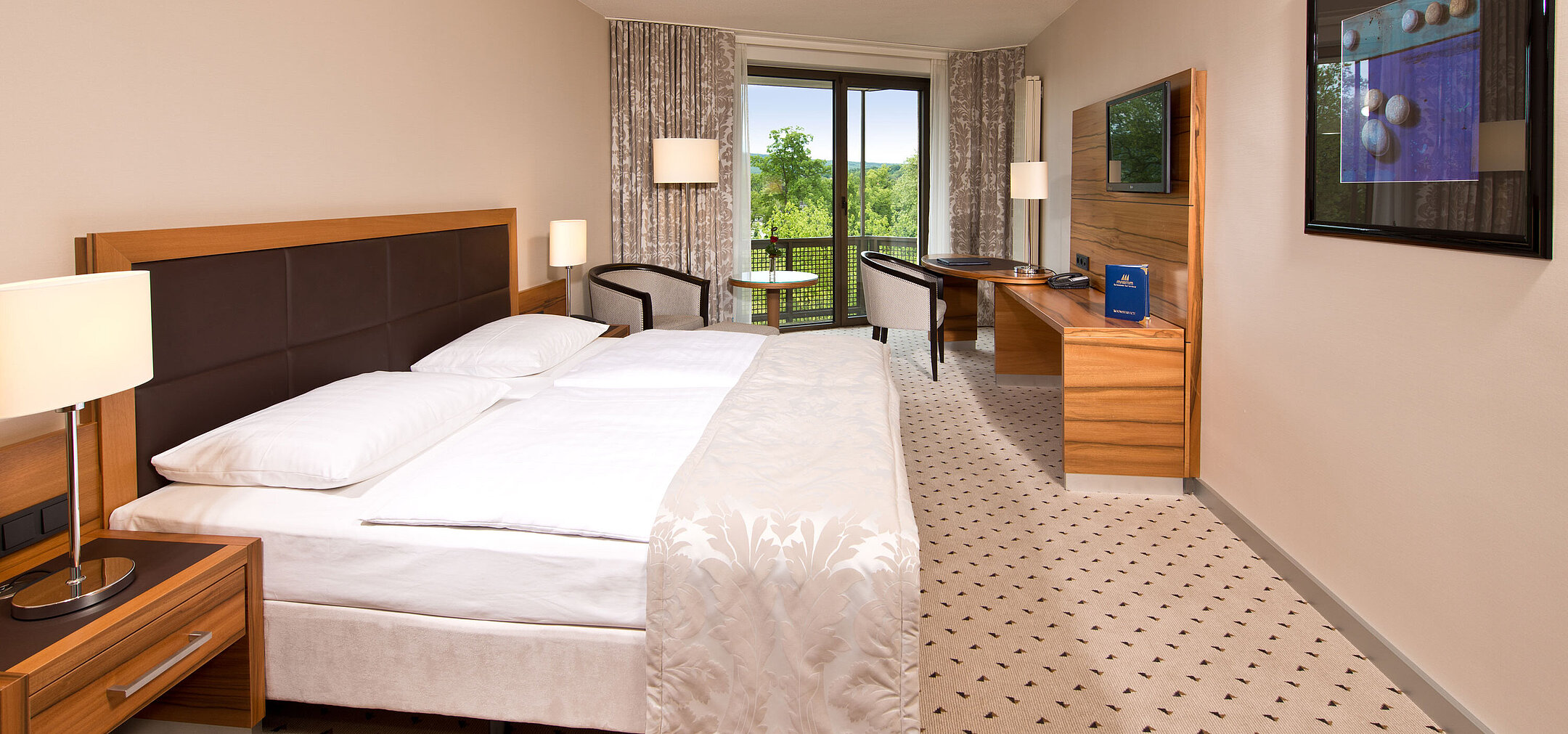 Comfort room Bright room at Maritim Hotel Bad Homburg with cozy bed, desk, and balcony with green view.