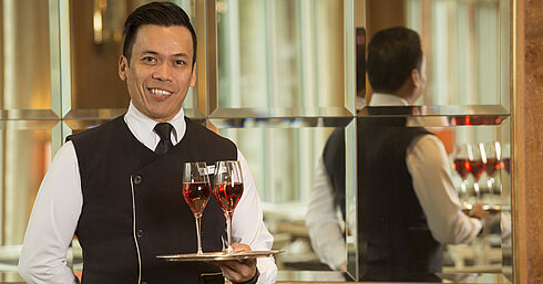 Maritim Service Waiter with two glasses of rosé wine on a silver tray at Maritim Hotel Stuttgart, friendly and professional