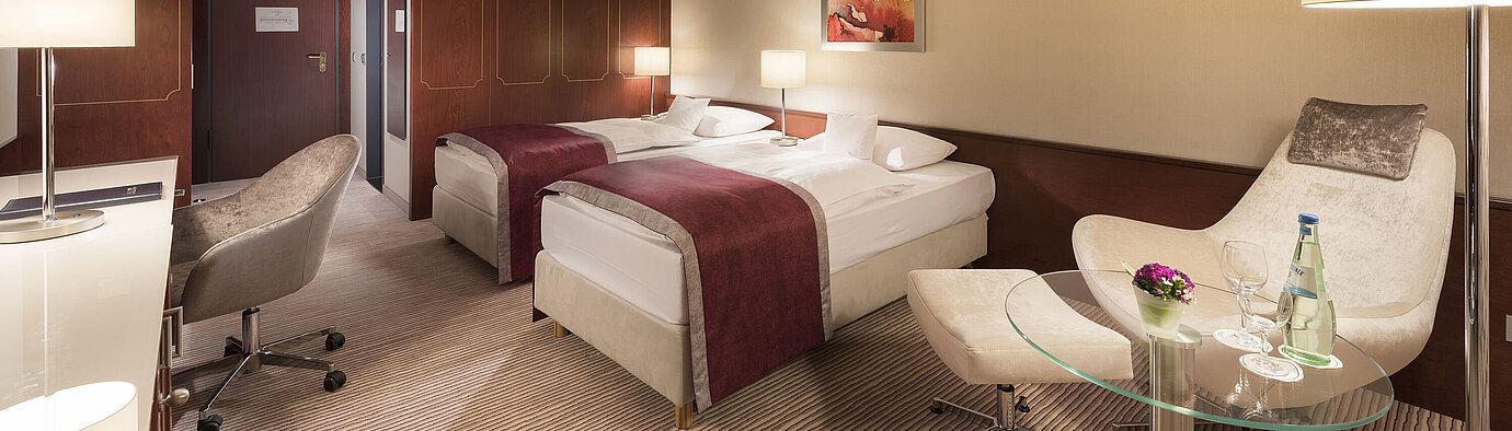 Comfort room Comfort room at Maritim Hotel Bonn, featuring two single beds, armchair, desk, and modern lighting.