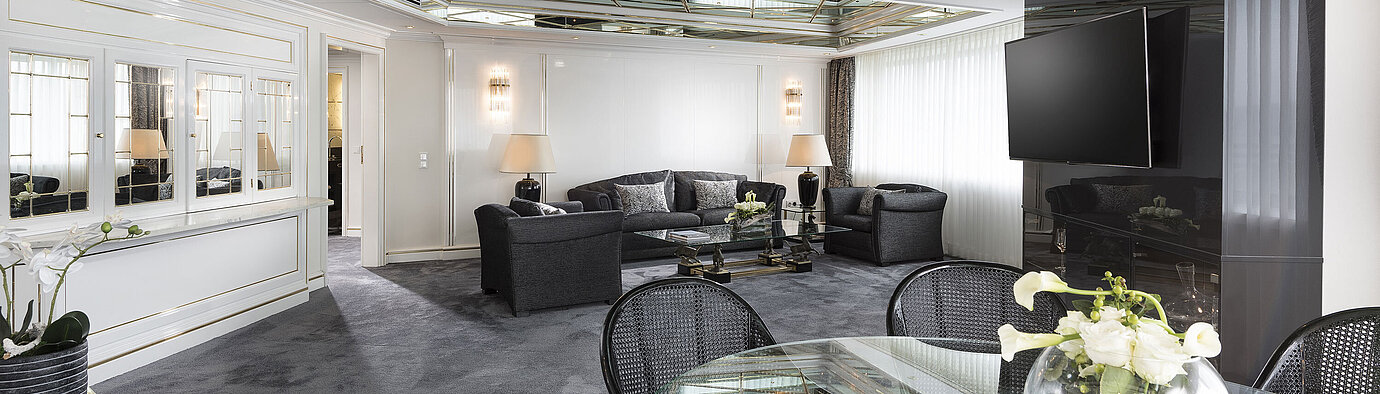 Luxury suite Stylish living room of the luxury suite at Maritim Hotel Bonn with mirrored ceiling, modern furniture, and large dining table.