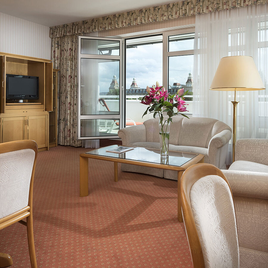 Junior suite Spacious living area with flowers, sofa, dining table and view at Maritim Hotel Bad Wildungen