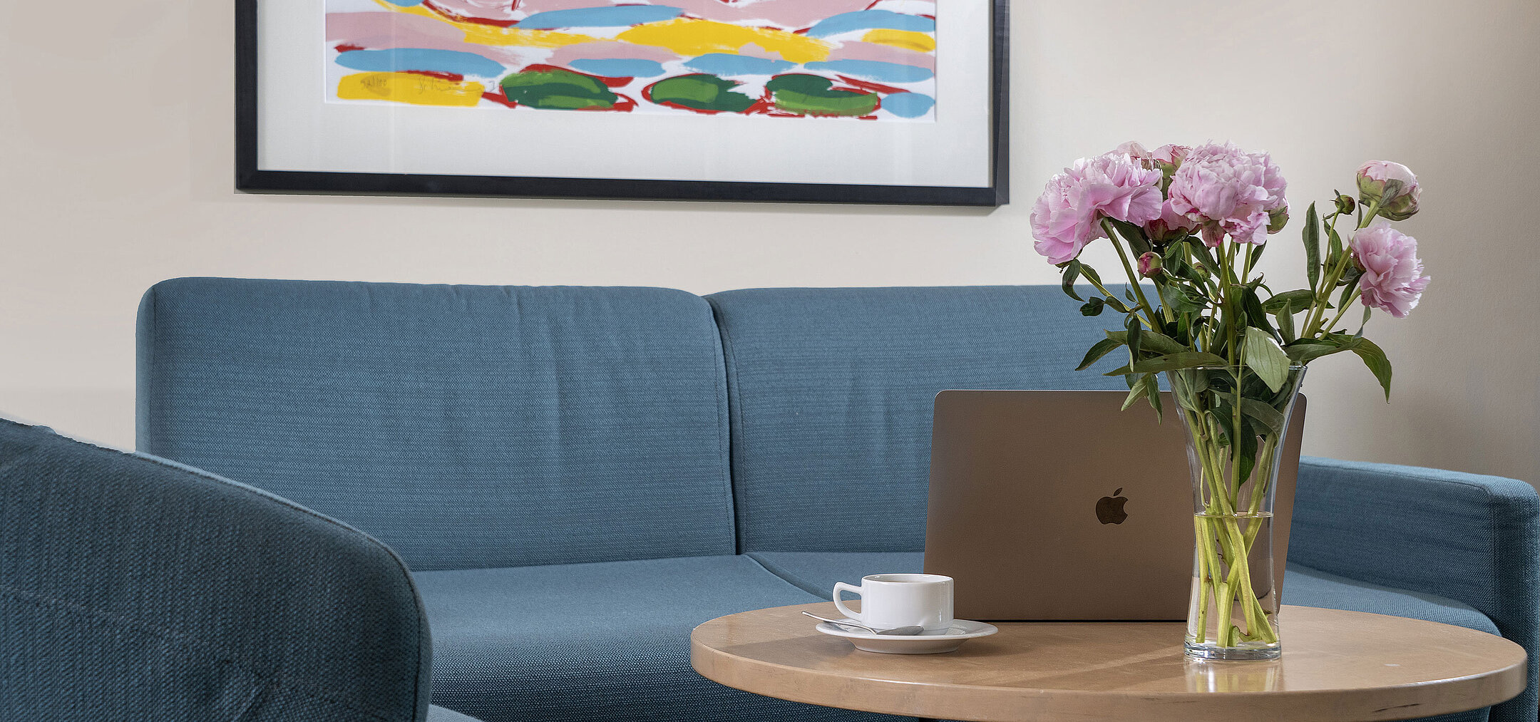 Suite ProArte Sala de estar moderna con sofá, mesa, flores y portátil en Maritim proArte Hotel Berlin