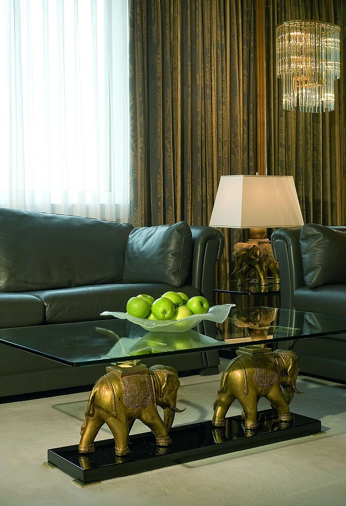 Suite Luxury Salón elegante con sofás de cuero, mesa de cristal y manzanas