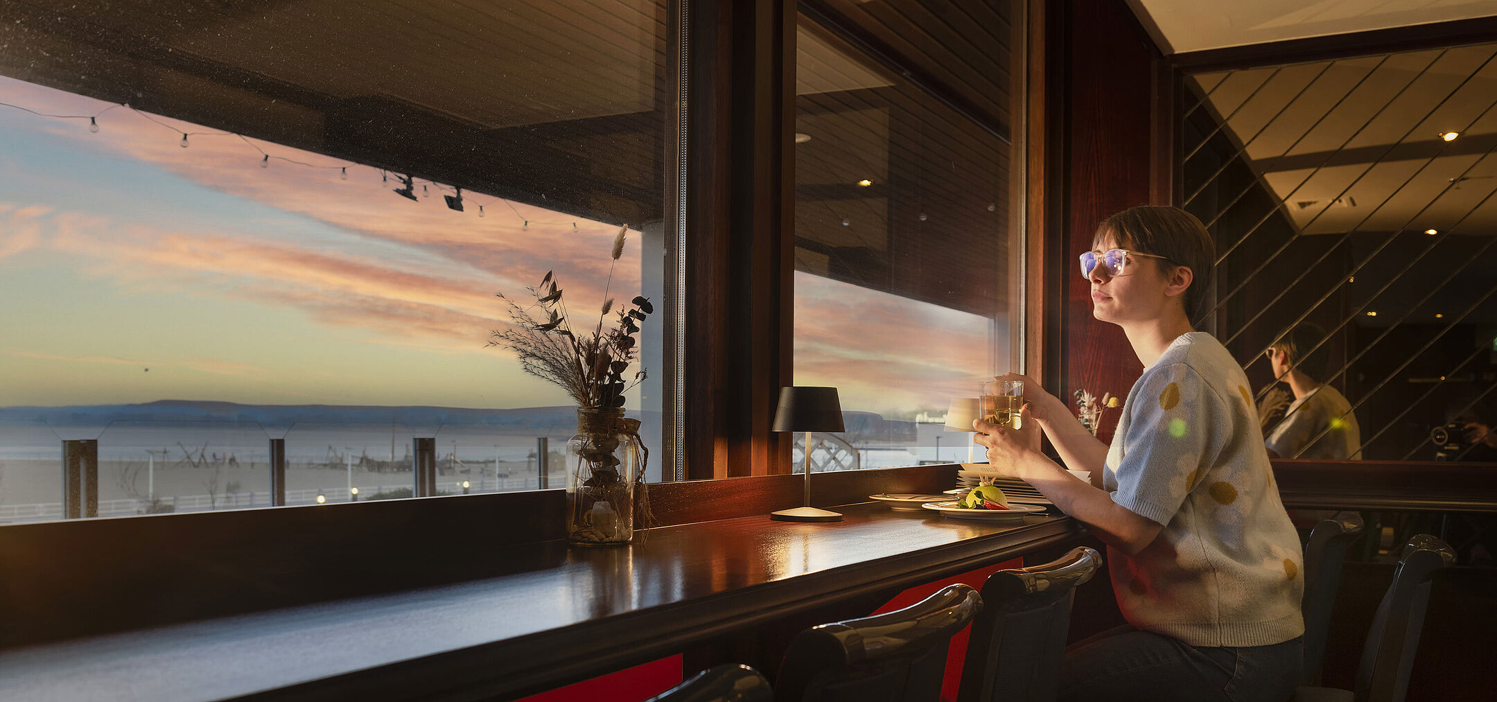 Pub sul Mar Baltico Ospite con drink alla finestra e vista sul tramonto al Maritim Hotel Travemünde