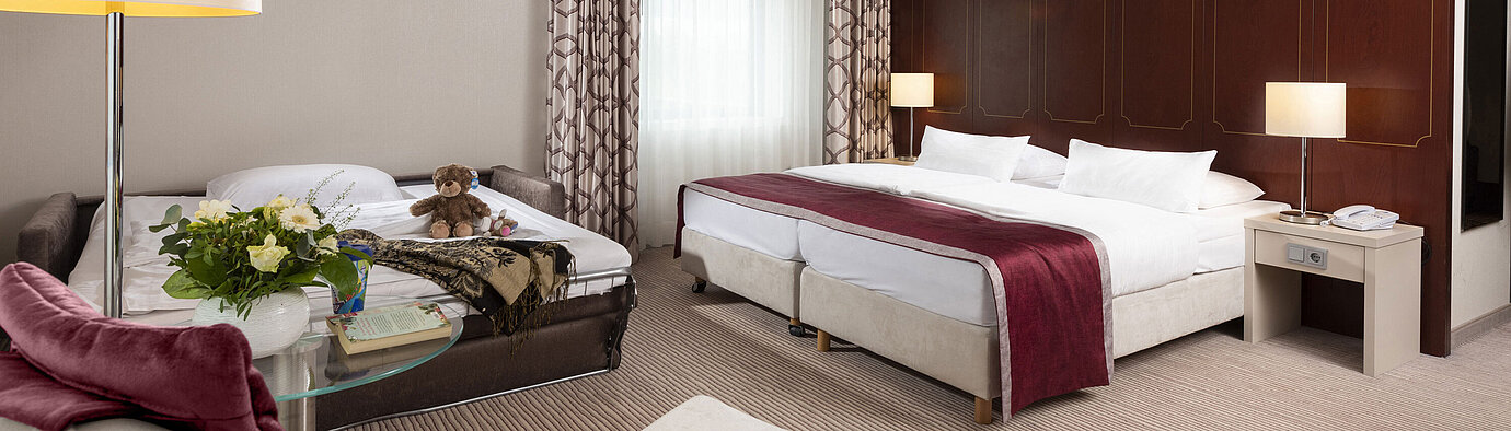 Comfort Family room Comfort family room at Maritim Hotel Bonn with a large double bed, pull-out sofa, armchair, and flower arrangement.