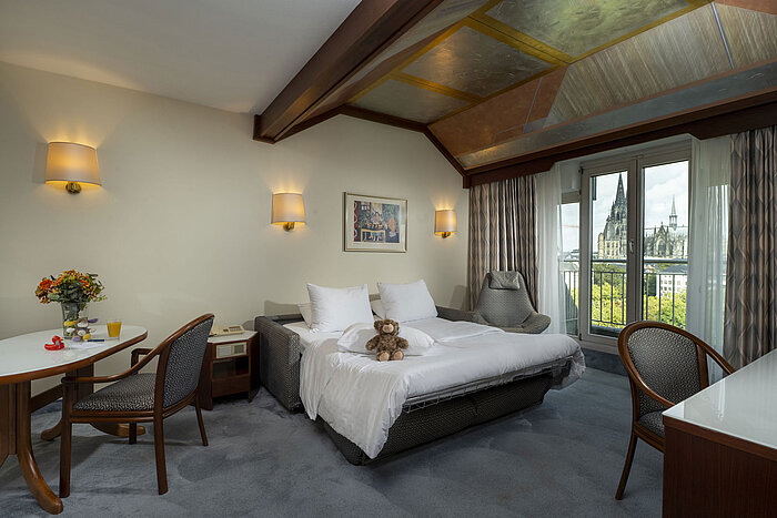 Suite di famiglia Camera familiare accogliente al Maritim Hotel Colonia con vista sul Duomo di Colonia e peluche sul letto.