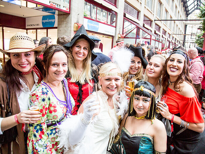 Mujeres con coloridos disfraces celebran un carnaval y sostienen copas de champán.