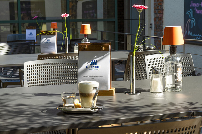 Terraza Cappuccino, agua y pastel en la terraza soleada del Maritim Hotel Stuttgart
