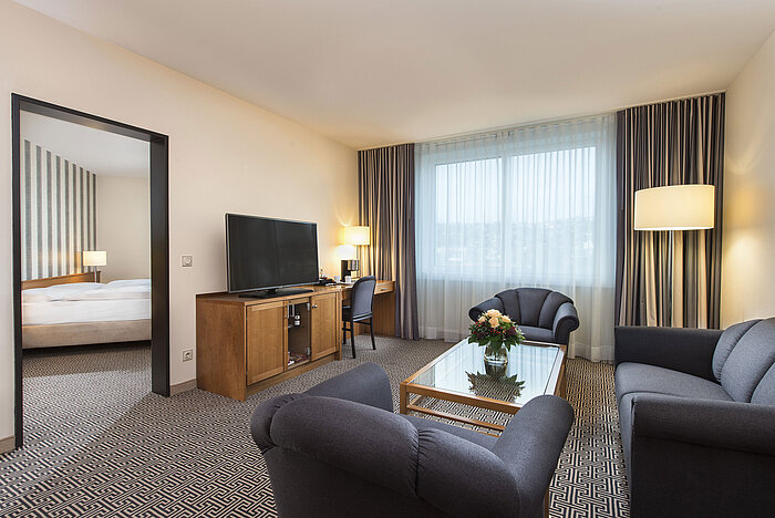 Suite Junior Sala amplia con sofá, sillón, TV y escritorio en la suite del Maritim Hotel Stuttgart