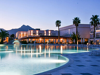 Pool Evening lights at the pool of Maritim Resort Calabria with palm trees and mountain backdrop