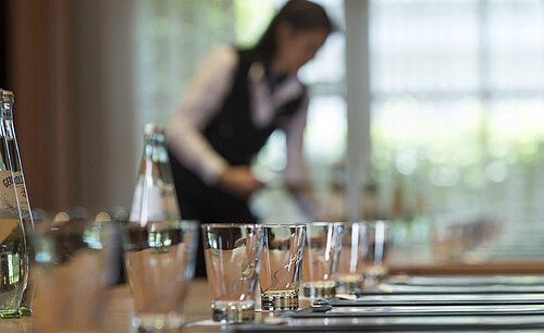 Preparing a meeting Staff member preparing conference table with glasses and water bottles for meeting