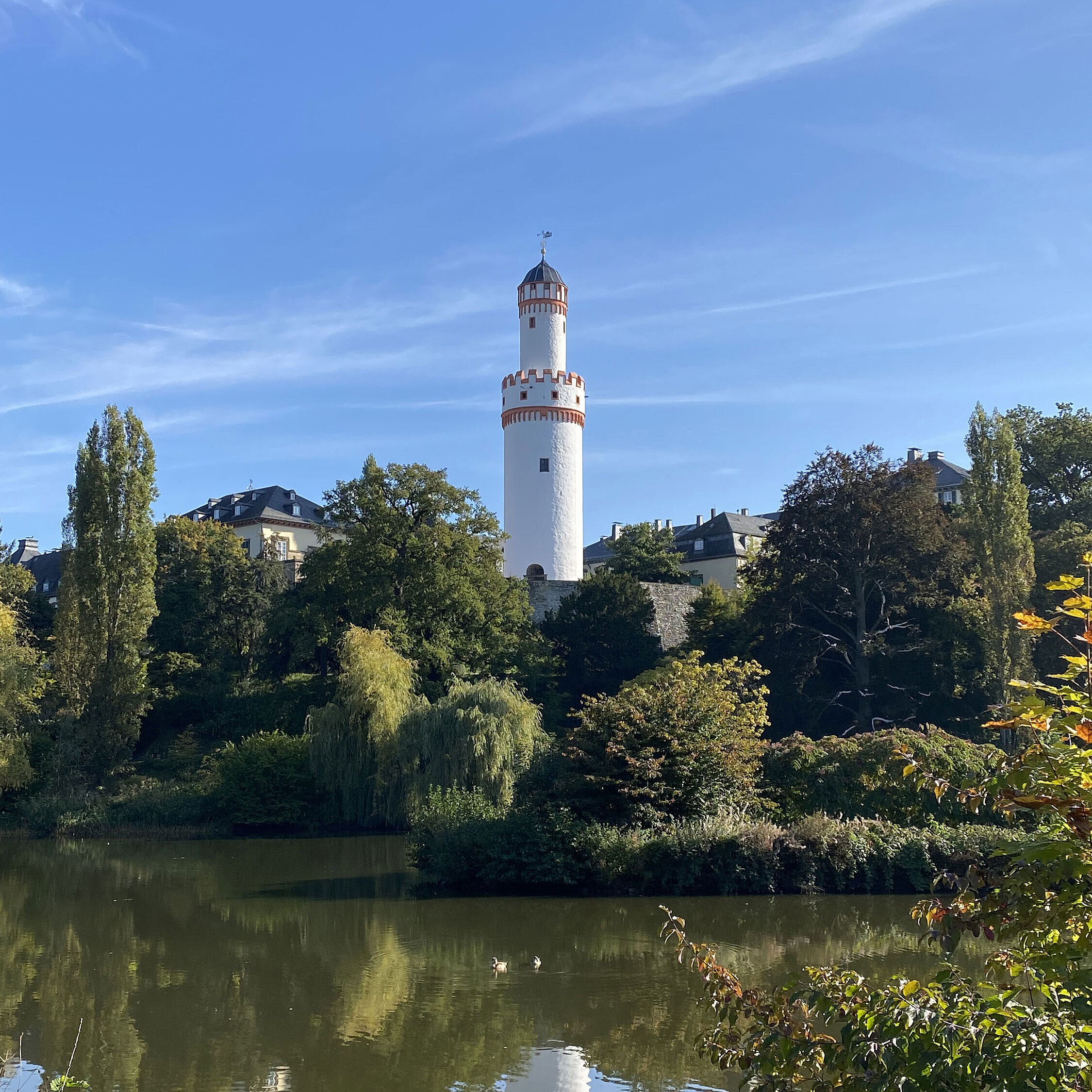 Bad Homburg Castle White tower in Bad Homburg with blue sky and surrounded by green nature.