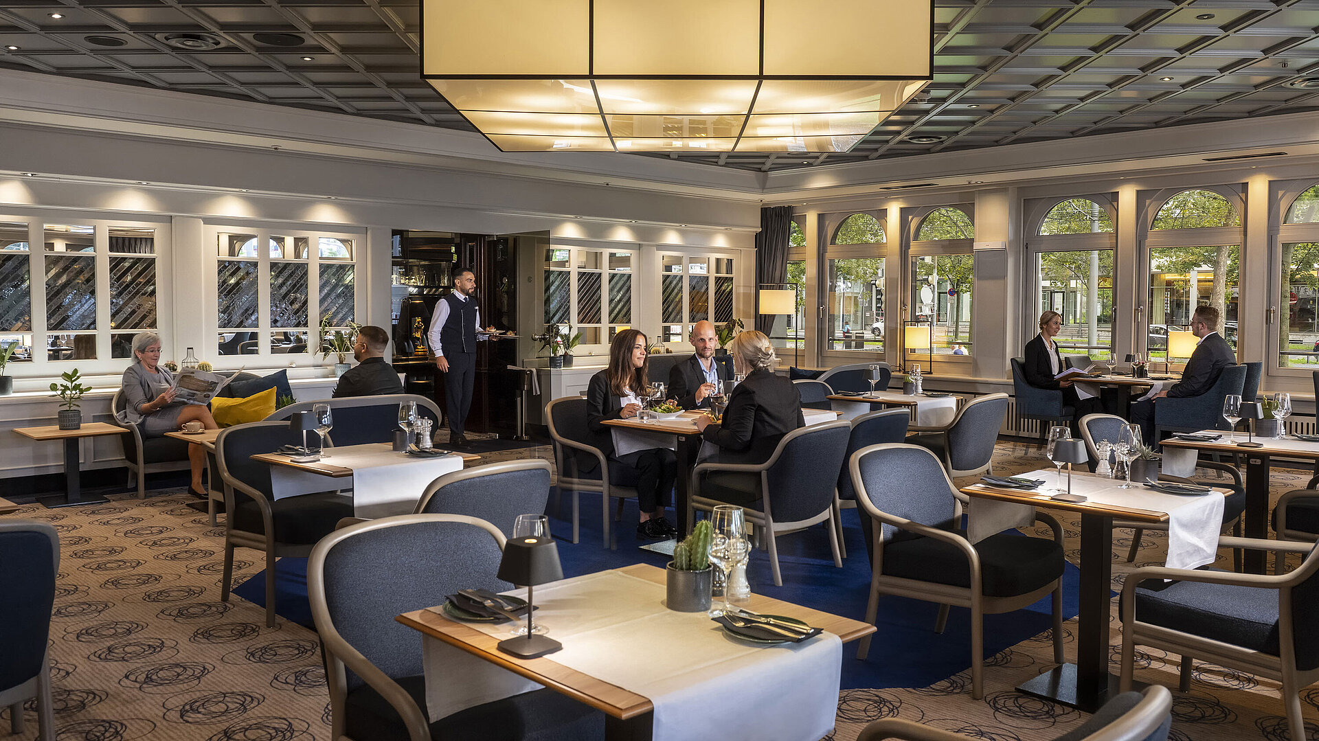 Restaurant Elegant restaurant at Maritim Hotel Darmstadt with guests dining and relaxing. Modern decor and large windows with a view.