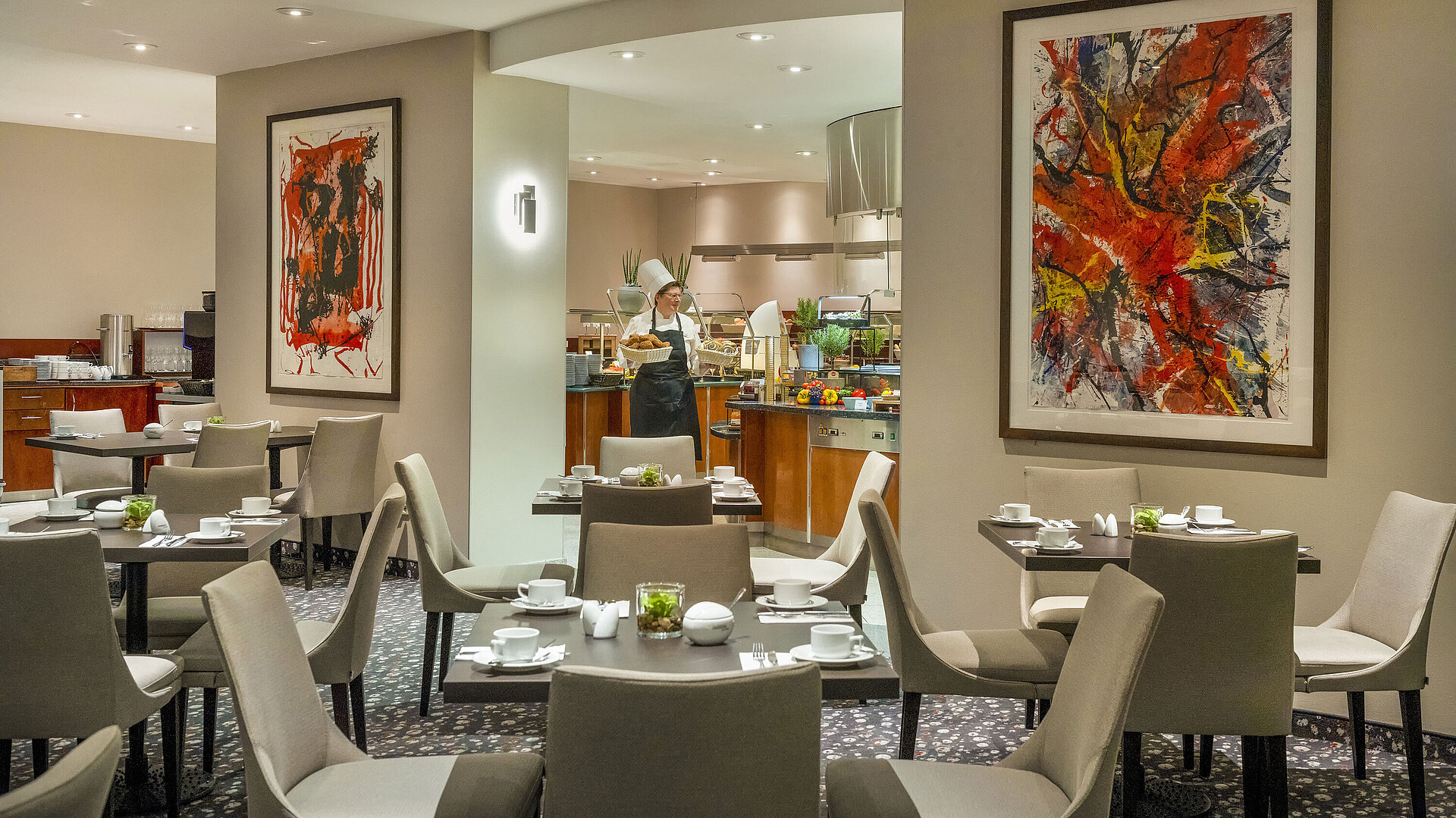 Ristorante Galerie Ristorante del Maritim proArte Hotel Berlin con arte moderna alle pareti, tavoli apparecchiati e uno chef al buffet.