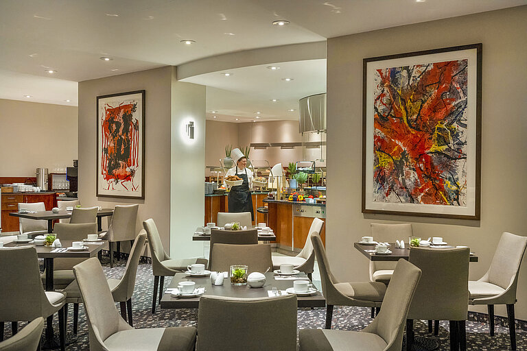 Ristorante Galerie Ristorante del Maritim proArte Hotel Berlin con arte moderna alle pareti, tavoli apparecchiati e uno chef al buffet.
