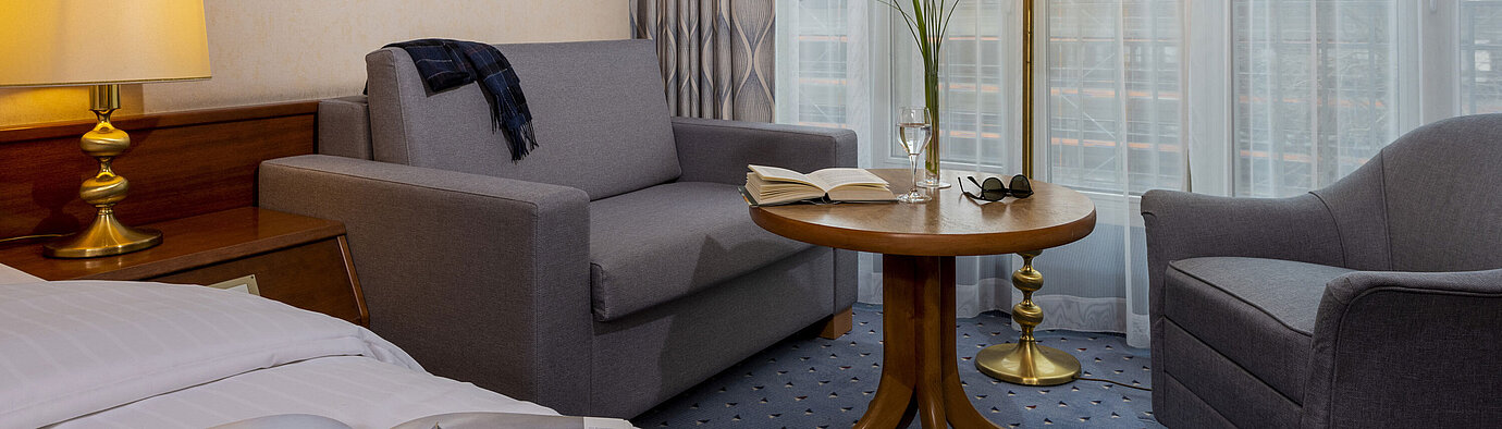 Camera Comfort Camera comfort del Maritim Hotel Köln, con accogliente area salotto, tavolo da lettura e arredi moderni.