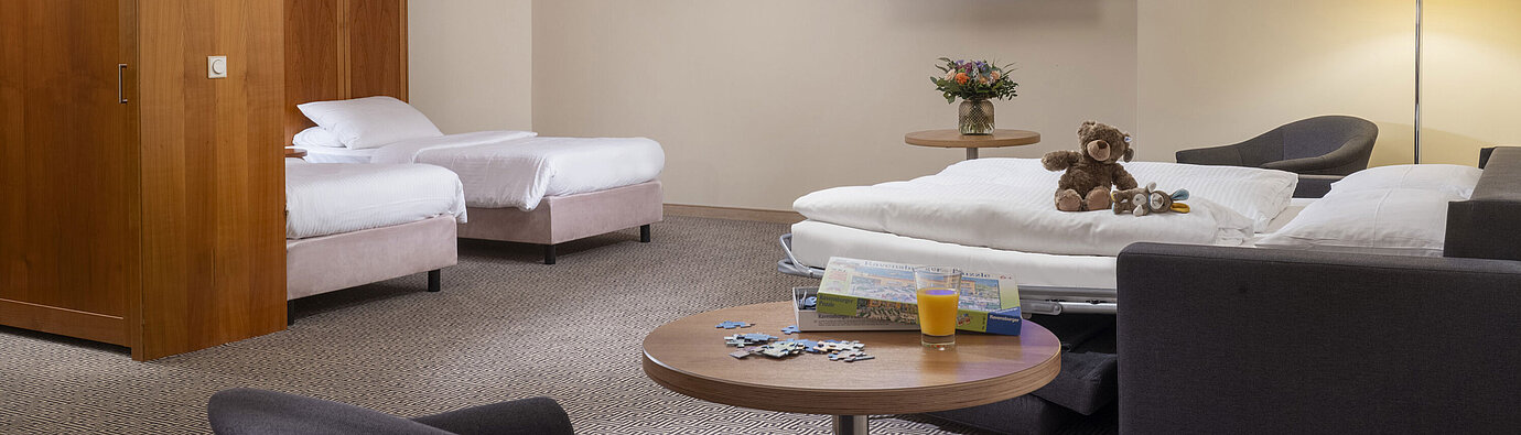 Habitación familiar Habitación familiar con sofá cama, juguetes y puzzle en el Maritim Hotel Stuttgart