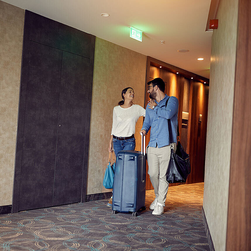 Llegada al hotel Pareja con maletas en el pasillo del hotel disfrutando su estancia