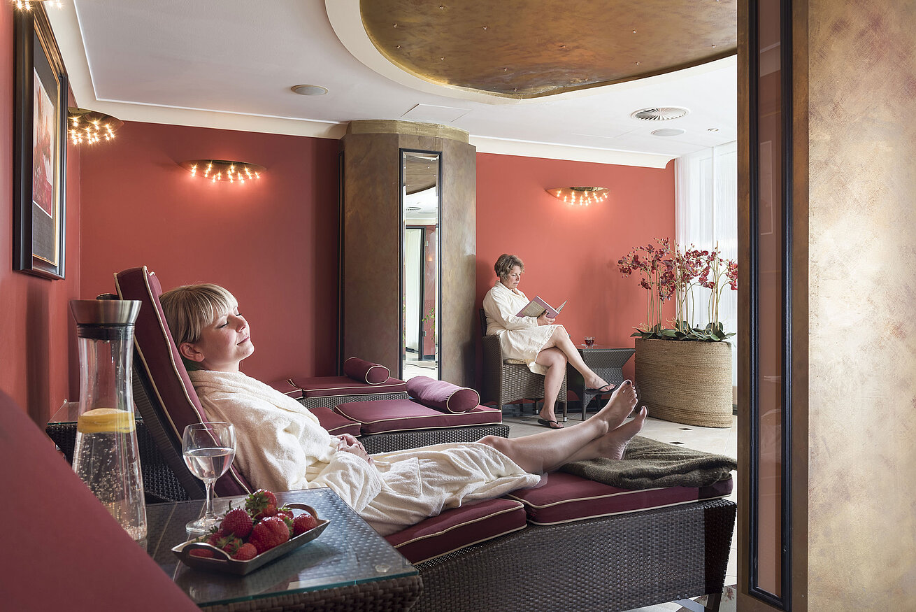 Aire de repos Salle de repos aux murs rouges au Maritim Seehotel Timmendorfer Strand, clients se relaxant sur des transats.